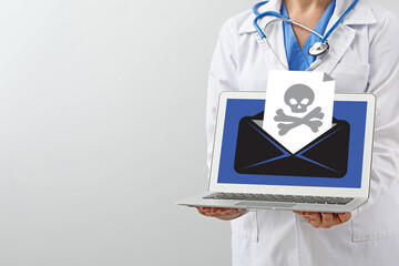 Female doctor with received infected email message on screen of laptop against light background