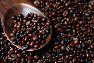 Scoop out ripe coffee beans using a large spoon made of wood and iron. Coffee beans scattered on the floor. Details texture of dark brown coffee beans. Graphic resourches for design template.