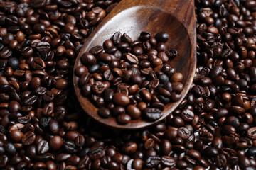 Scoop out ripe coffee beans using a large spoon made of wood and iron. Coffee beans scattered on the floor. Details texture of dark brown coffee beans. Graphic resourches for design template.