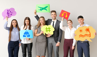Group of business people holding speech bubbles with different drawings on light background