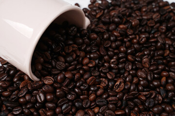 The scattered coffee beans came out of the white cup. Blend of coffee bean with cup isolated on...