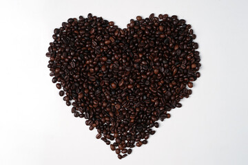 Handcrafted arrangement of coffee beans shaped to resemble a heart, symbol of love to commemorate Valentine's Day. Blend of coffee beans and symbol of love for the background concept.
