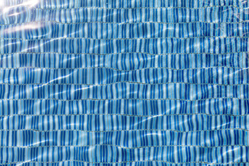 Fototapeta premium Sun reflection in clear clean and bright blue water of swimming pool, Water wave under swimming pool with light reflecting. Texture background.