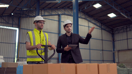 Warehouse worker and manager checking product in a large warehouse