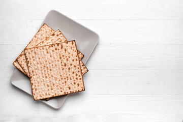 Plate with Jewish flatbread matza for Passover on white wooden background