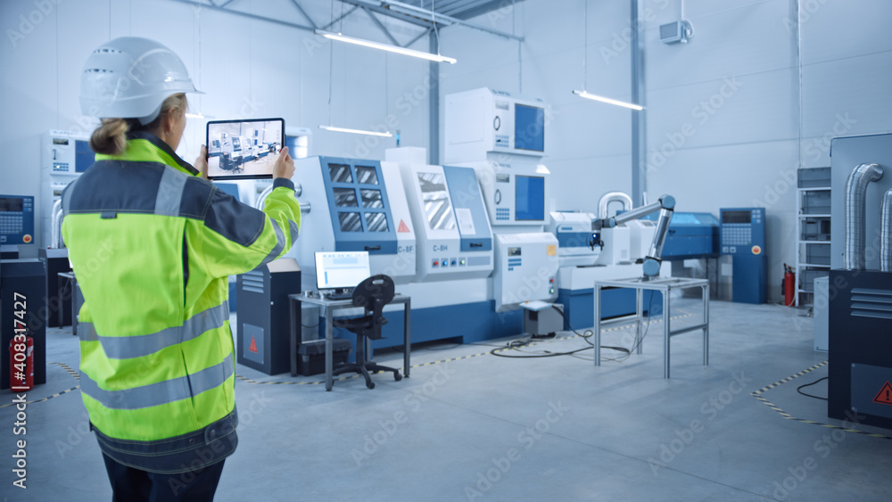 Leinwandbilder Industry 4.0 Modern Factory: Female Engineer Uses Digital Tablet Computer with Augmented Reality to Visualize Workshop Mapping, Floor Layout. Facility with High-Tech CNC Machinery and robot arm