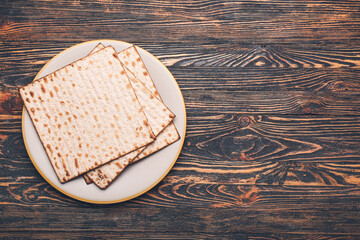 Plate with Jewish flatbread matza for Passover on wooden background