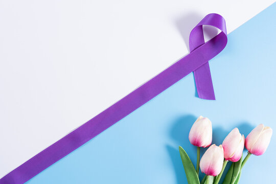 World cancer day, purple ribbon and tulip flower on with and blue background with copy space for text. Healthcare and medical concept. - Powered by Adobe