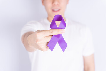 World cancer day, hands holding purple ribbon on grey background with copy space for text....