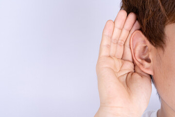 man hearing loss or hard of hearing and cupping his hand behind his ear isolate grey background, Deaf concept.