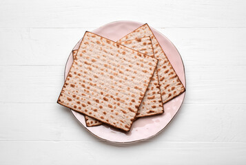 Plate with Jewish flatbread matza for Passover on white wooden background