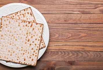 Plate with Jewish flatbread matza for Passover on wooden background