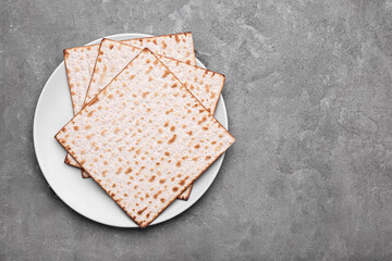 Plate with Jewish flatbread matza for Passover on grey background