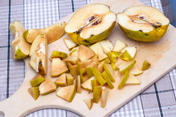 the quince, sliced to make jam, lies on a wooden chopping board