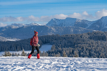 nice active senior woman snowshoeing in the Allgaeu Alps near Oberstaufen with view on the...