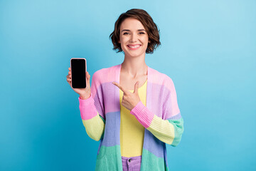 Photo portrait of woman pointing finger at phone with blank space isolated on pastel blue colored...