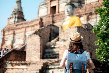 Asian woman tourists carrying a backpack and wearing a hat Visit Wat Yai Chaimongkol, the historical archaeological site of Phra Nakhon, Ayutthaya.