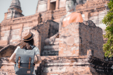 Asian woman tourists carrying a backpack and wearing a hat Visit Wat Yai Chaimongkol, the historical archaeological site of Phra Nakhon, Ayutthaya.