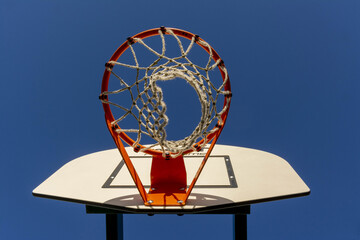 Low angle shot of a basketball hoop and the plain blue sky