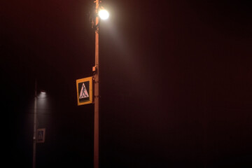 Fototapeta na wymiar minimalist photo of city lights covered by fog in the night above the pedestrian cross-walk sign