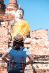 Asian woman tourists carrying a backpack and wearing a hat Visit Wat Yai Chaimongkol, the historical archaeological site of Phra Nakhon, Ayutthaya.