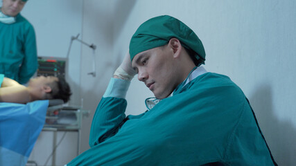 Fototapeta na wymiar Sad surgeon sitting on floor in corridor at hospital