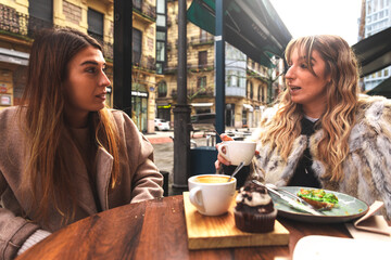 Two friends having breakfast at a terrace on a winter morning in Donostia-San Sebastian; Basque Country.