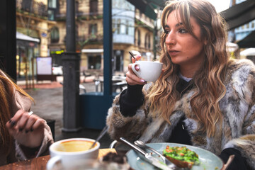 Two friends having breakfast at a terrace on a winter morning in Donostia-San Sebastian; Basque Country.