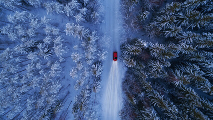 Winter landscape with red car driving at night. Lights of car and winter snowy road in dark forest, big fir trees covered snow. Top down view.  - 408321497