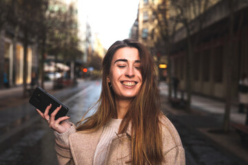 Young caucasian brunette woman using a smartphone at the street