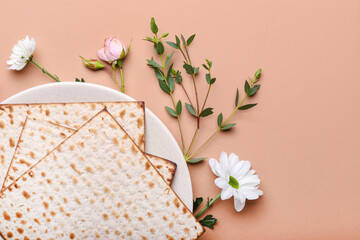 Plate with Jewish flatbread matza for Passover and flowers on color background