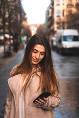 Young caucasian brunette woman using a smartphone at the street