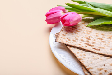 Plate with Jewish flatbread matza for Passover and flowers on color background, closeup