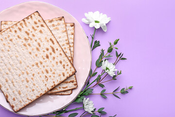 Plate with Jewish flatbread matza for Passover and flowers on color background