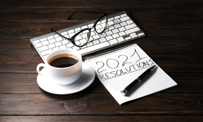 Old wood desk table with black coffee and laptop computer, notebook and eye glasses.