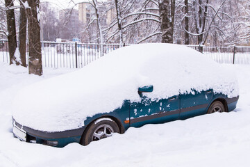 Blue car under snow in snowbank after snowfall and blizzard	
