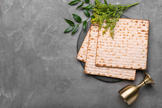 Jewish flatbread matza for Passover and cup on grey background