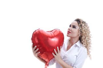young woman with curly hair and a white shirt hugs a red balloon in the form of a heart. Concept for valentine's day or women's day, mother's day.