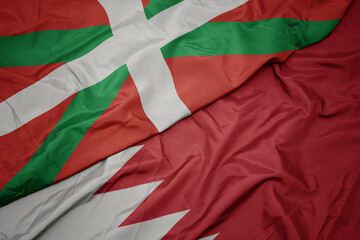 waving colorful flag of bahrain and national flag of basque country.