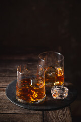 Two glasses of the whiskey with ice isolated on a dark background