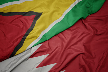 waving colorful flag of bahrain and national flag of guyana.