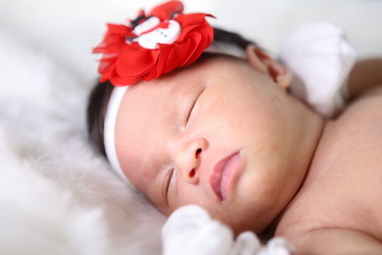 A beautiful Asian newborn girl wearing a headband sleeping on a white soft blanket, Infant, babyhood concept and copy space - Image