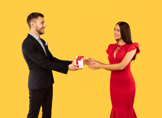 Boyfriend Giving Girlfriend Gift Box With Valentine Present, Yellow Background