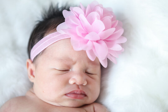 A beautiful newborn girl wearing a pink headband and sleeping on a white soft blanket, Infant, babyhood concept and copy space - Image