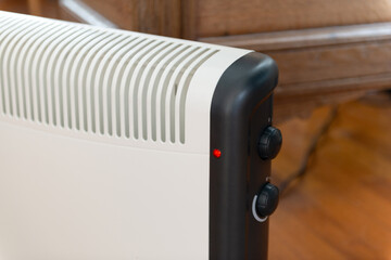 Détail d'un radiateur électrique d'appoint posé au sol dans une maison