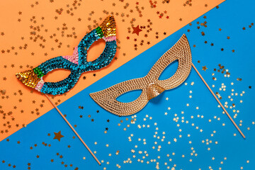 Carnival masquerade masks and gold glitter confetti. Top view, Close up on blue and orange colors...