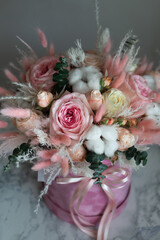 A bouquet of flowers of pink shades of roses and dried flowers in a gift box.