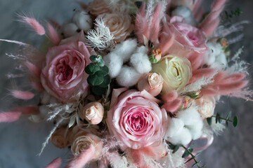 A bouquet of flowers of pink shades of roses and dried flowers in a gift box.