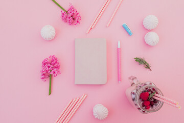 Tasty smoothie with straws, marshmallow, diary, pen and pink flowers on pink.