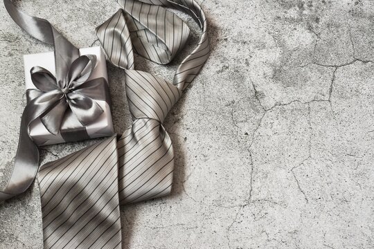 Happy father's Day. Gift box and tie on a gray concrete background. Copy space, flat lay. Greeting card.